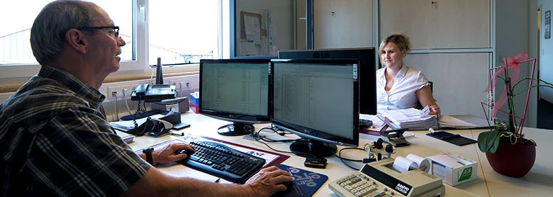 Arbeitsplatz in der Kanzlei mit zwei Bildschirmen, an denen eine Buchhaltung geöffnet ist