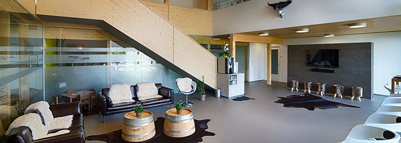 Eingangs- und Wartebereich mit Holztreppe, Ledersofas und Fässern als Beistelltische